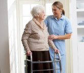 caregiver assisting senior woman in walking