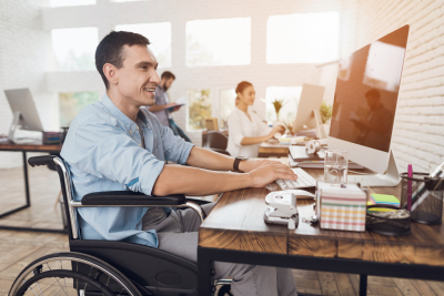 Person in the wheelchair works in the office at the computer